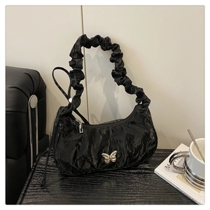 Detailed view of the silver butterfly metal buckle on black pleated shoulder bag