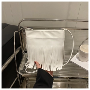 Detail of white PU leather crossbody bag featuring bohemian style long fringe tassels