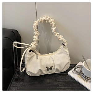 Close-up of cream crescent bag with silver butterfly buckle and pleated shoulder strap