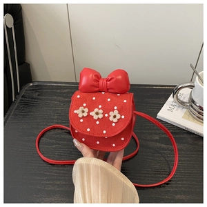 Détail d'un petit sac bandoulière rouge à pois avec fleurs en peluche et nœud