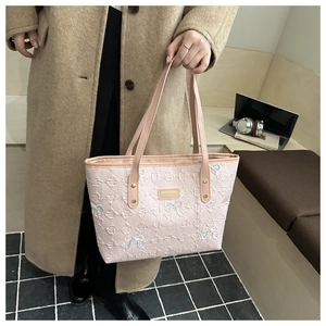Detail of pink tote bag with embossed lattice texture and colorful woven bow design
