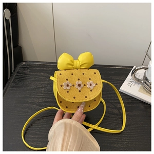 Détail du mini sac bandoulière jaune avec un grand nœud et des fleurs tricotées