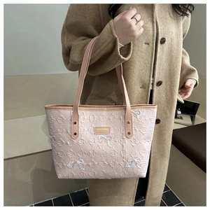 Close-up of pink quilted tote bag with embroidered bows and monogram pattern
