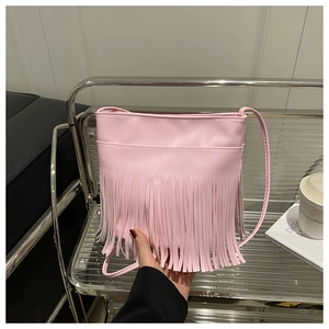 Close-up of pink faux leather bag featuring long bohemian tassels and stylish shoulder strap