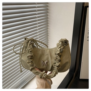 Detail of light green pleated underarm bag with silver butterfly and scrunchie handle