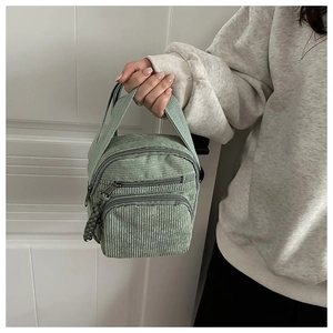 Détail du sac à main en velours côtelé vert clair avec poches zippées multicouches