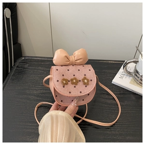 Détail d'un sac bandoulière rose pour enfant avec fleurs en peluche et un grand nœud