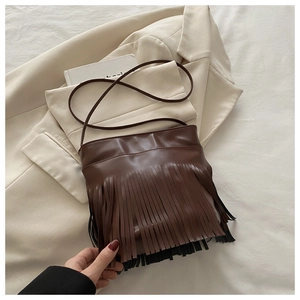 Detail of dark brown leather crossbody bag featuring stylish fringe and slim shoulder strap