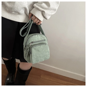 Sac bandoulière vert en velours côtelé porté par un mannequin dans un look décontracté