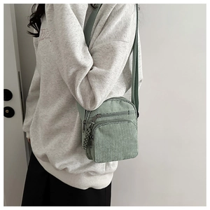 Détail du sac bandoulière en velours côtelé vert clair avec plusieurs poches et texture