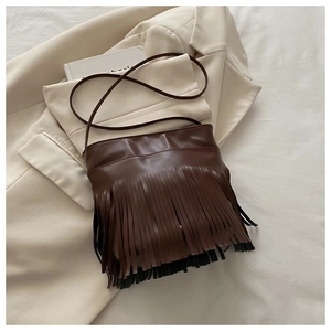 Detail of dark brown retro tassel crossbody bag with long fringe on a stylish neutral setting