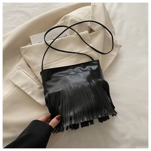 Detail shot of black PU leather shoulder bag featuring long fringe tassels in boho style
