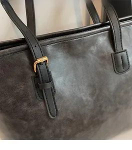 Close-up of vintage leather texture and golden metal buckle on large tote bag
