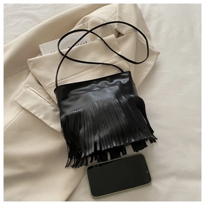 Detail of a black tassel shoulder bag with matte leather finish shown on a blazer