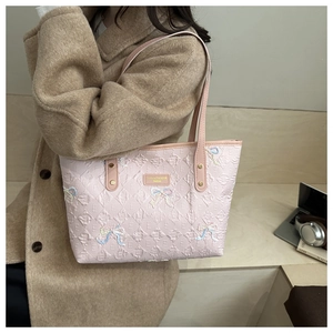 Detailed view of light pink tote bag with embossed textures and sequin bow accents