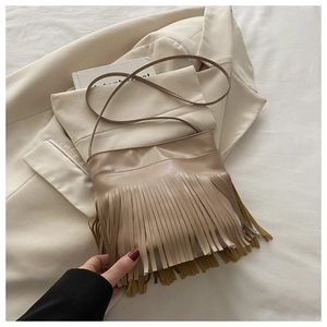 Close-up of bohemian light khaki crossbody bag featuring dense fringe tassels and PU leather