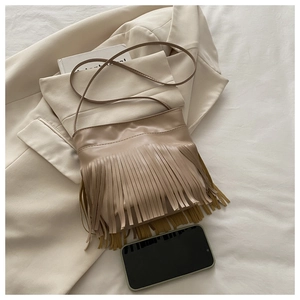 Close-up of beige fringe crossbody bag with matte synthetic leather texture and long tassels