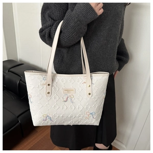 Detail of white tote bag with colorful 3D bow embroidery and textured surface