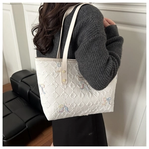 Close-up of quilted tote bag with colorful butterfly embroidery and golden rivets