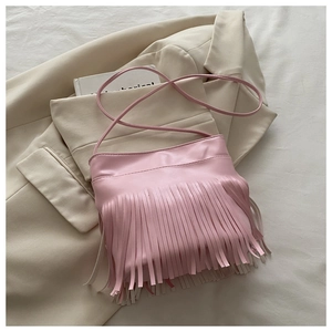 Detailed view of pink tassel shoulder bag displayed on a stylish beige blazer background