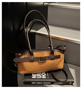 Détail d'un sac bandoulière vintage en daim marron avec boucle dorée sur des livres
