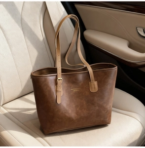 Detail of vintage brown leather tote bag on car seat with golden fashion lettering