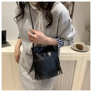 Detail view of black PU leather crossbody bag with dense fringe accents in retro style