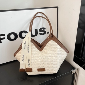 Chic beige straw tote bag with brown leather trim and decorative ribbon strap