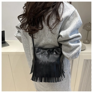 Detailed back view of a black crossbody bag with ethnic style fringe and slim shoulder strap