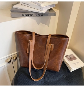 Detail of vintage brown leather tote bag with elegant gold lettering on stripe cushion