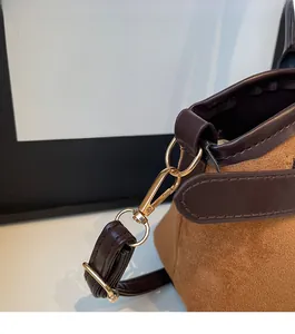 Détail macro du fermoir doré et du daim marron sur un sac à bandoulière vintage