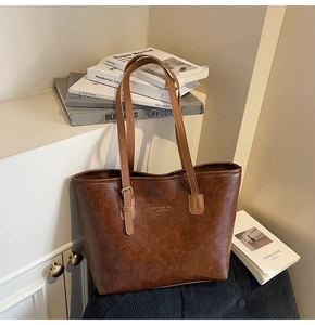 Detail of brown faux leather tote bag with gold lettering and adjustable shoulder strap
