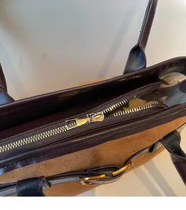 Détail de la fermeture éclair dorée sur le sac cabas en daim et cuir marron