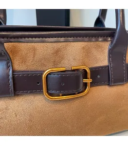 Gros plan sur la boucle dorée et le cuir suédé bicolore d'un sac bandoulière rétro