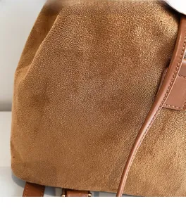 Détail de la texture en daim caramel doux et coutures fines sur un sac à dos vintage