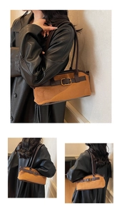 Détail d'un sac à bandoulière en daim marron avec boucle dorée et finitions en cuir