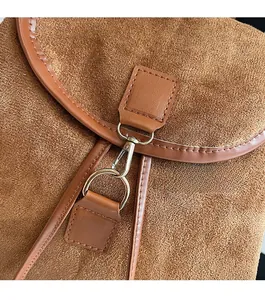 Détail du fermoir en métal argenté brillant sur un sac à bandoulière en daim marron