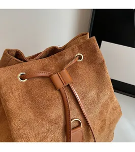 Détail du sac seau en daim marron avec cordon de serrage et anneaux en métal doré