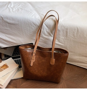 Close-up of caramel leather tote bag showing grainy texture and FASHION & BAG lettering