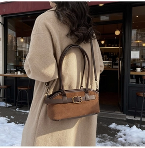Détail d'un sac porté épaule en daim marron avec boucle dorée et finitions en cuir chic