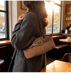 Détail d'un sac fourre-tout en daim marron avec boucle dorée dans un café d'automne