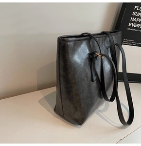 Detail of dark grey PU leather tote bag with vintage texture and sleek shoulder strap