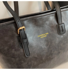Macro view of vintage matte leather texture and adjustable gold buckle on large tote bag
