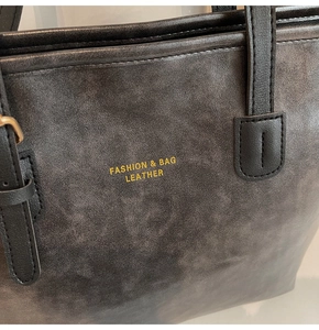 Detail of dark grey tote bag with vintage texture and gold fashion lettering