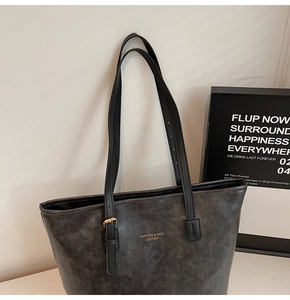 Close-up of retro gray leather tote bag with gold metal buckle and fashion logo text
