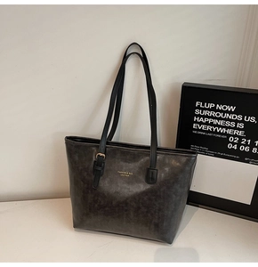 Detail of vintage grey tote bag with gold lettering and matte synthetic leather texture