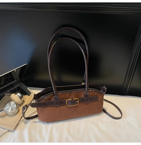 Détail du sac bandoulière en daim marron montrant la texture mate et la boucle dorée