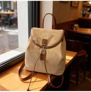 Vue détaillée du sac à dos en daim beige avec finitions en cuir marron sur bois
