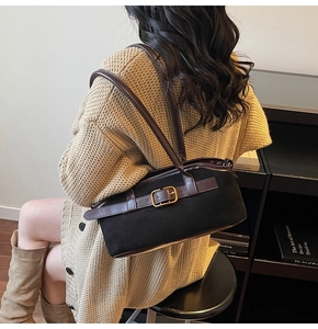 Détail du sac bandoulière noir mat avec bandoulière en cuir marron et boucle dorée