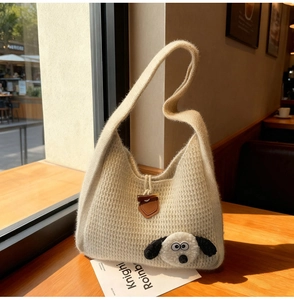 Détail d'un sac fourre-tout en tricot beige avec chiot en peluche et boucle en cuir